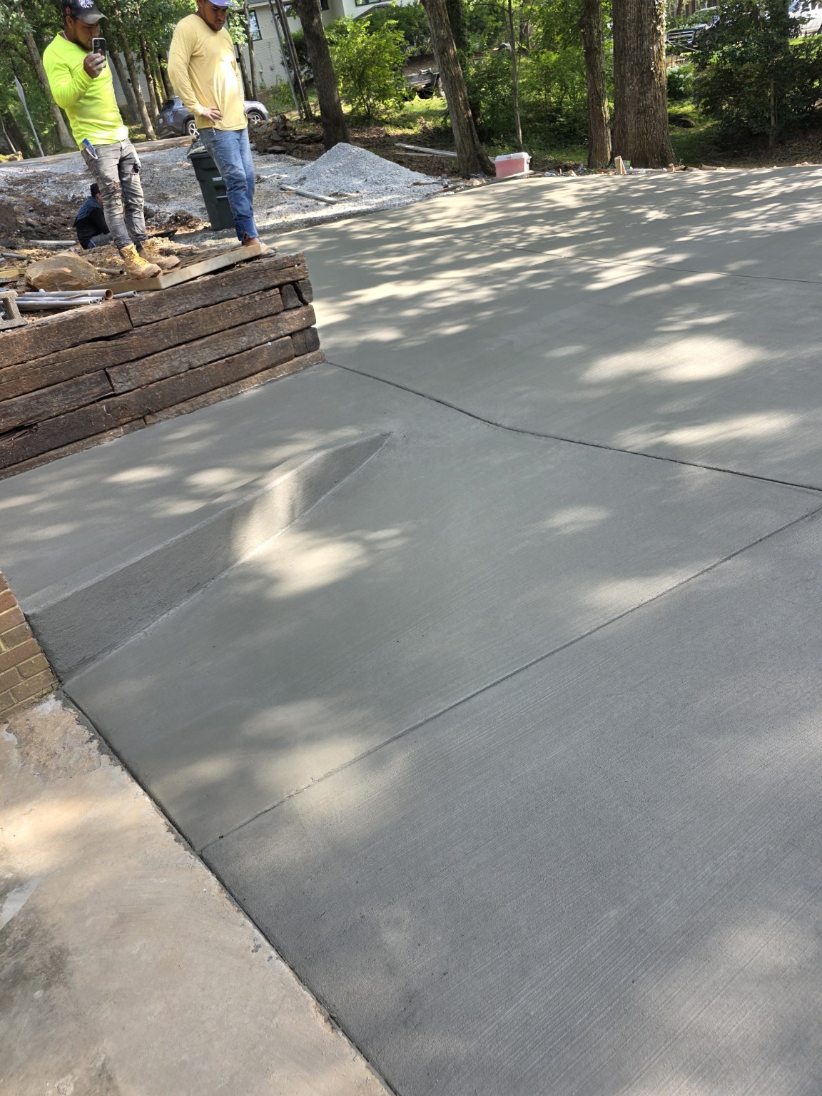 Crew finishing fresh concrete around a curved retaining wall