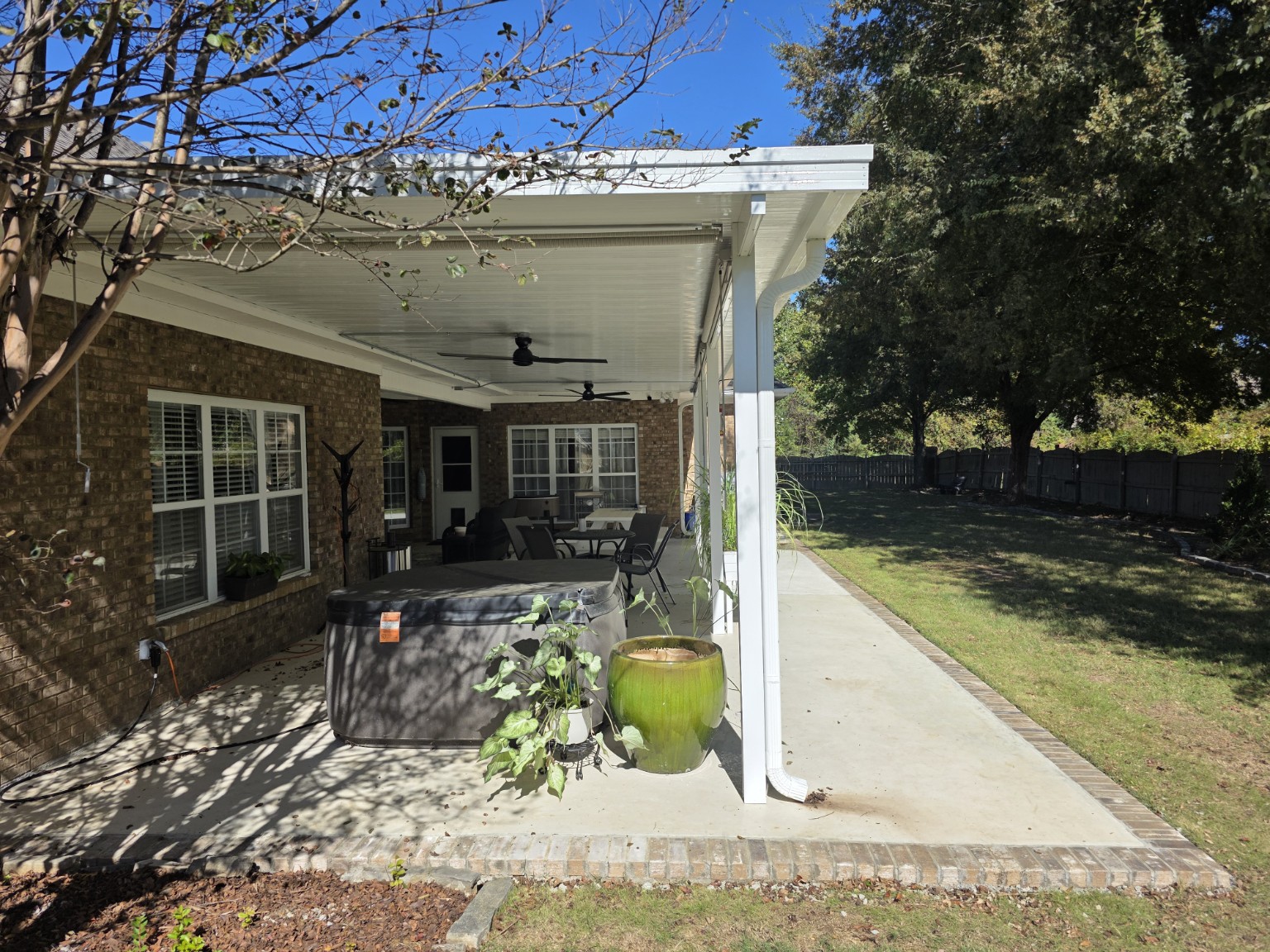 Finished covered porch with concrete floor, ceiling fans, lighting, columns, and gutters